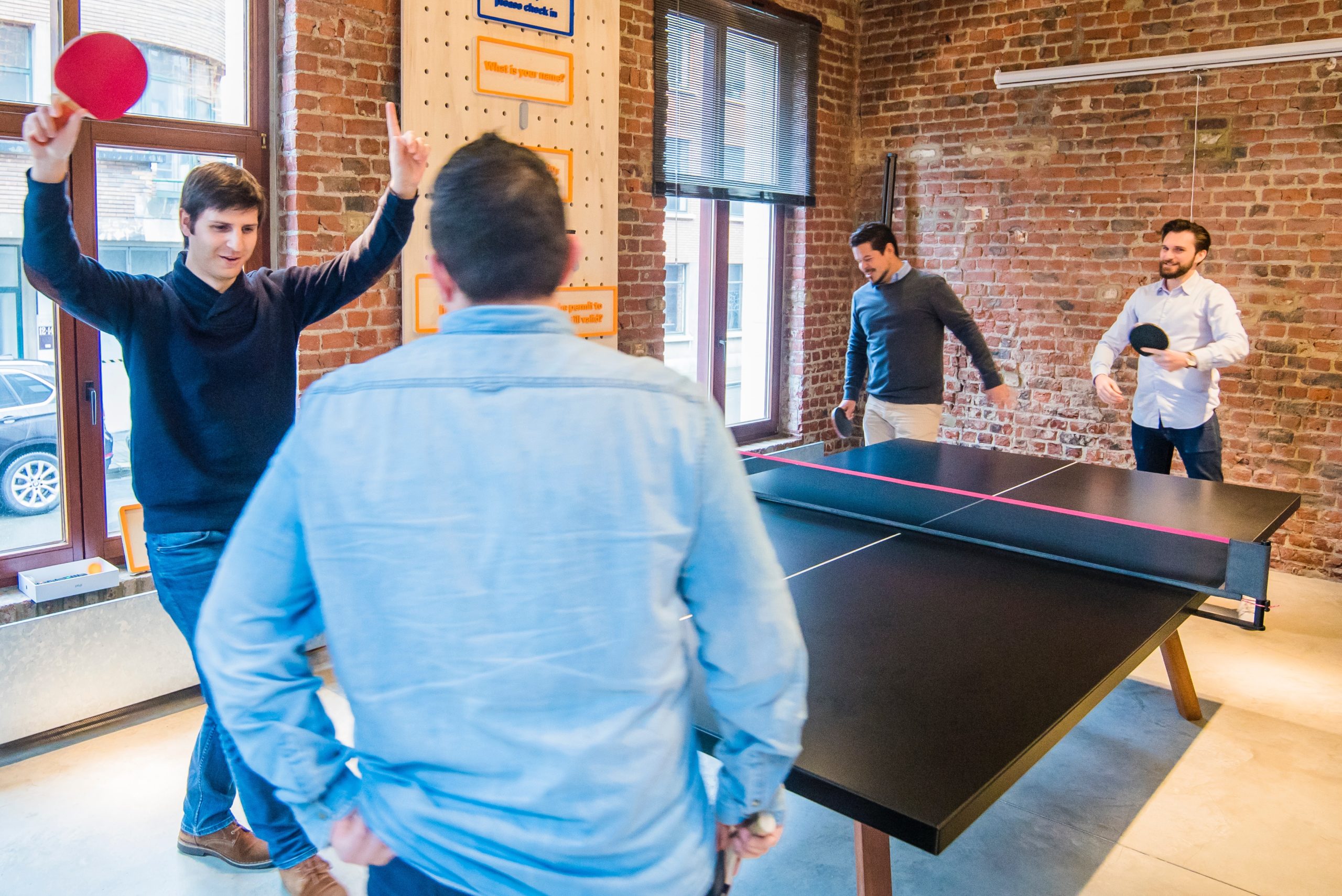 A group of people play ping pong at their office ping pong table