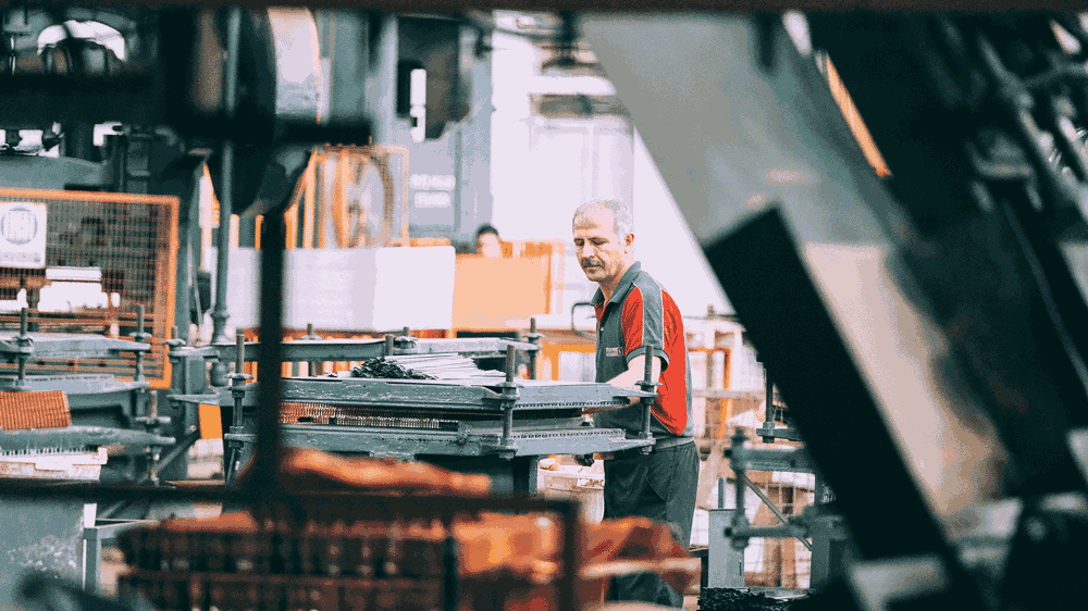 A person working on some type of machinery in a factory.