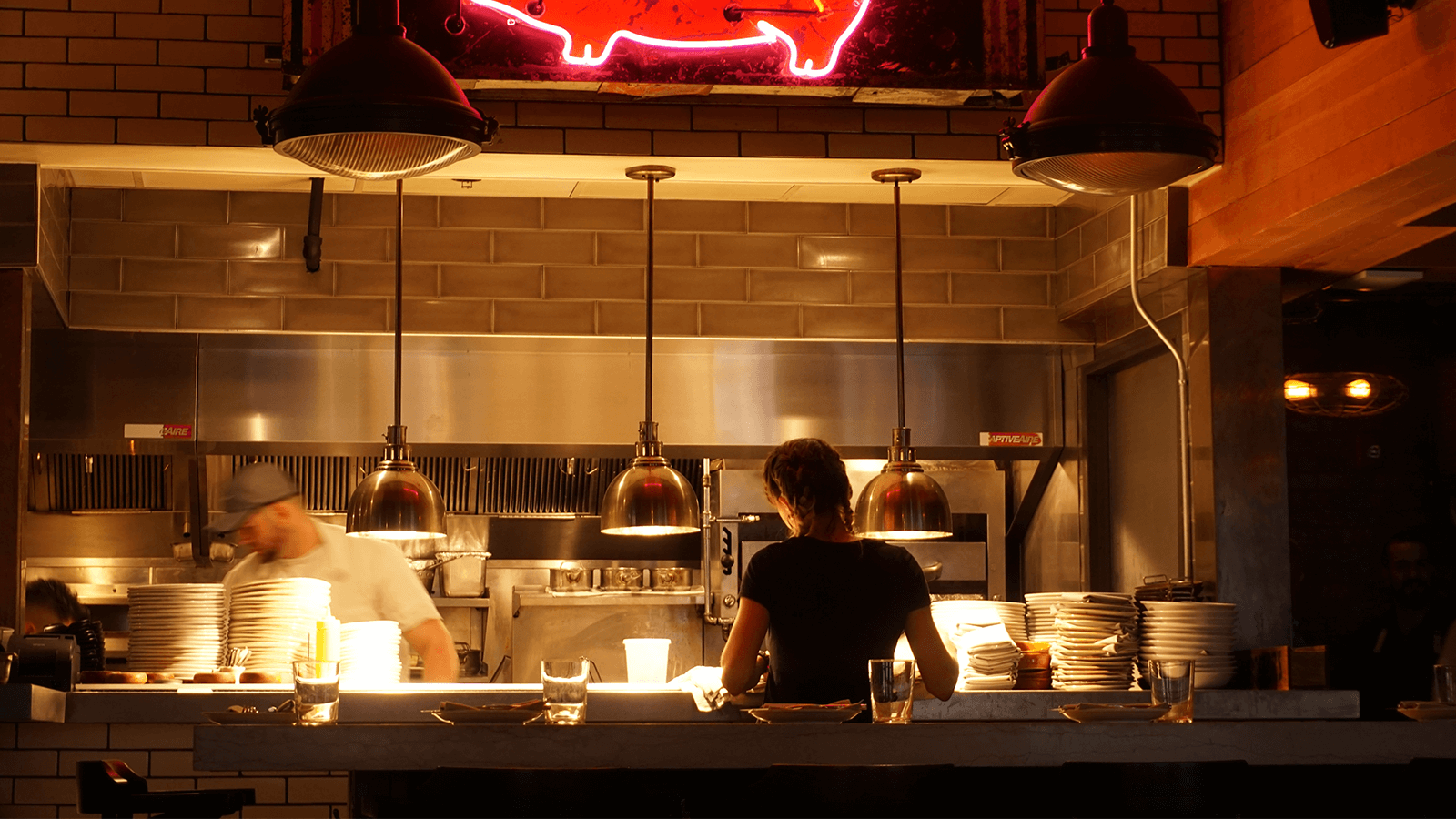 Restaurant staff works behind the counter in a dimly lit establishment