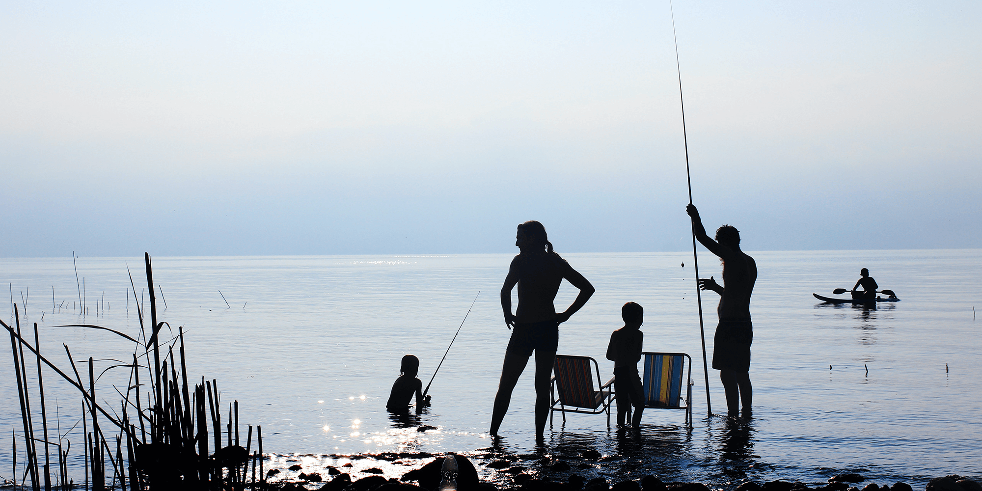 A family of four is fishing on the beach together.